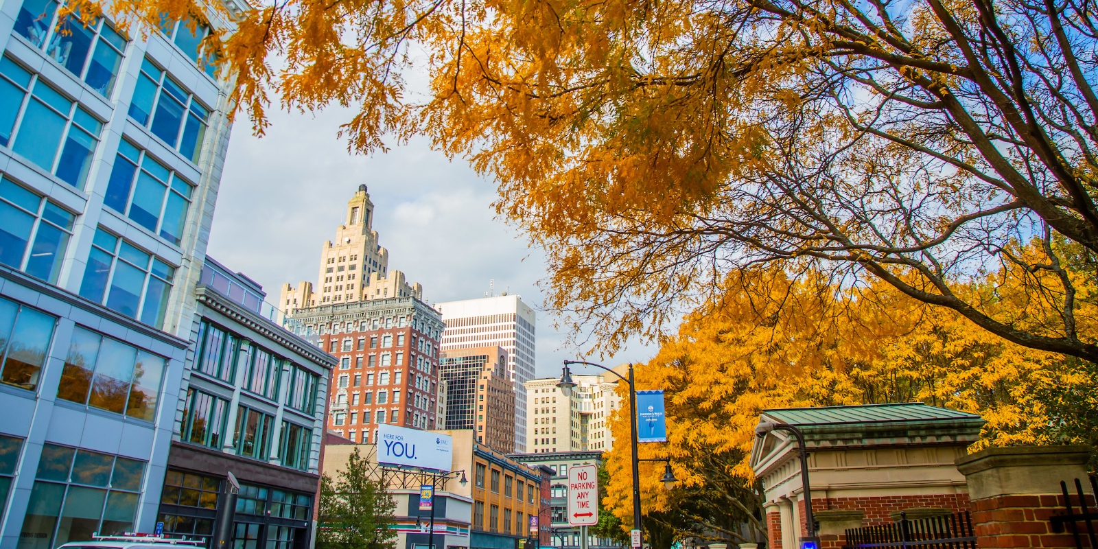 Outside Gaebe Commons during the Fall. Billboard in the midground reads "Here for YOU"