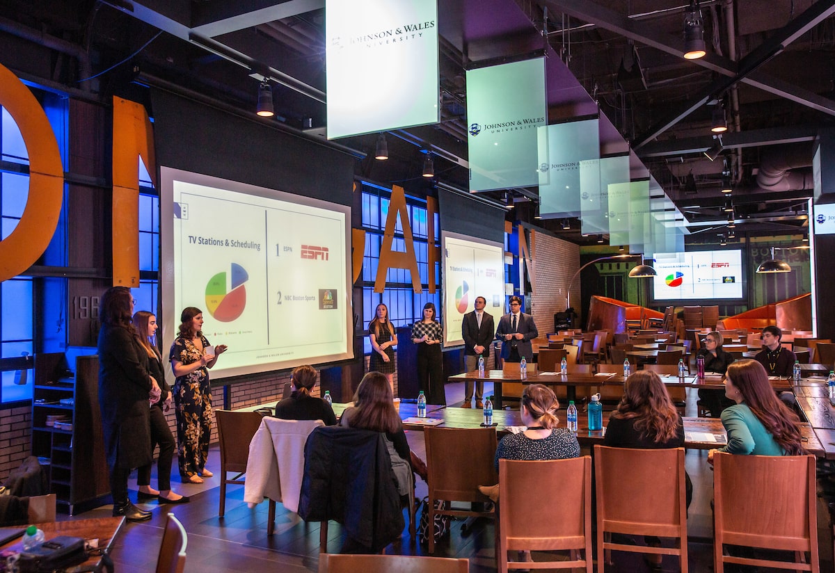 Students presenting in front of large screen