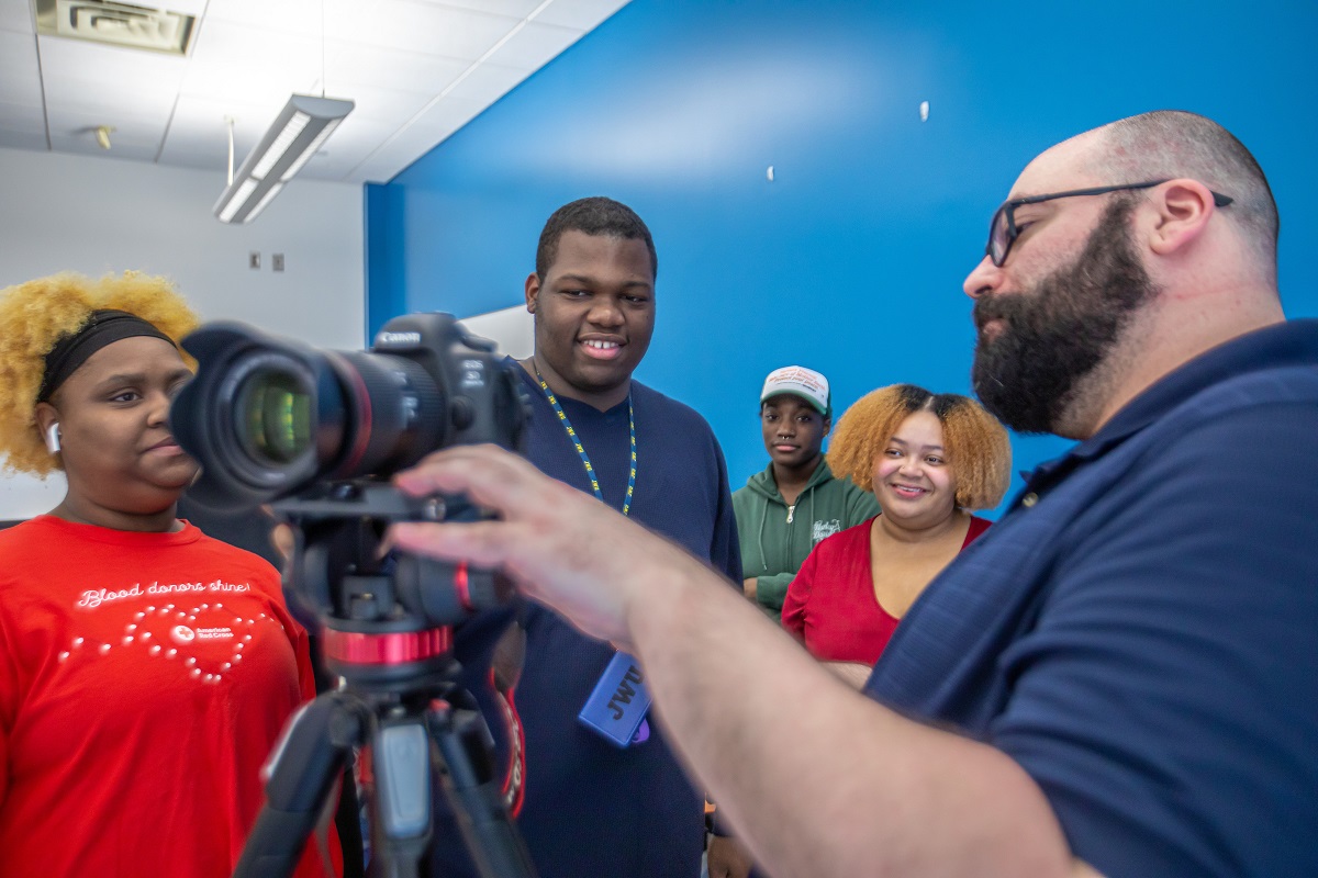 Media professor showing students how to use equipment 