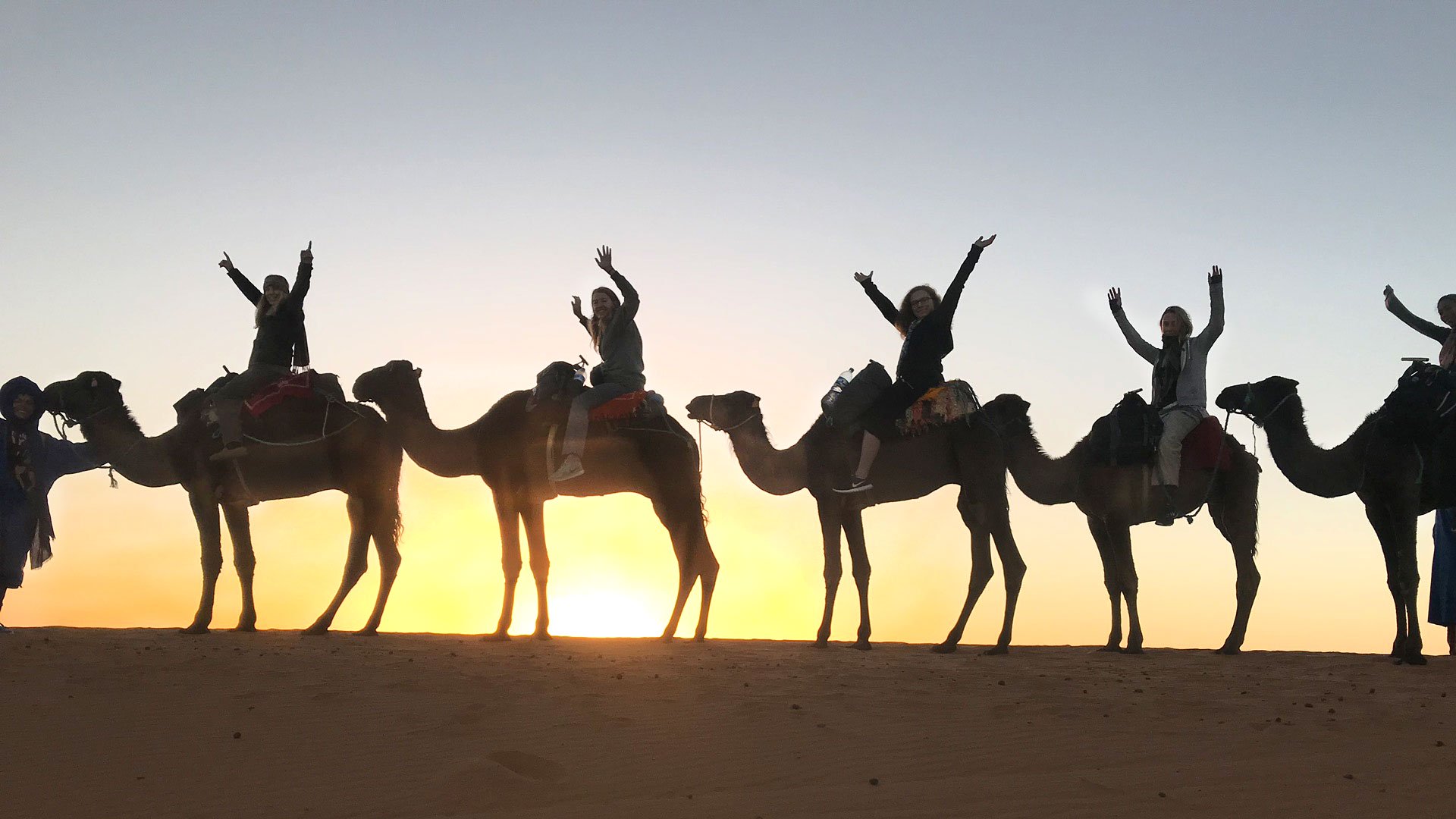 Students on camelback enjoy the Sarhara sunset.