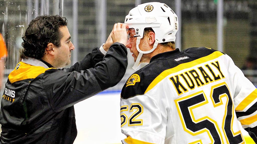 Jason Berger adjusting a Bruin's player's visor before a game