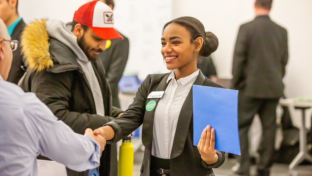 Female student shakes hand at career fair