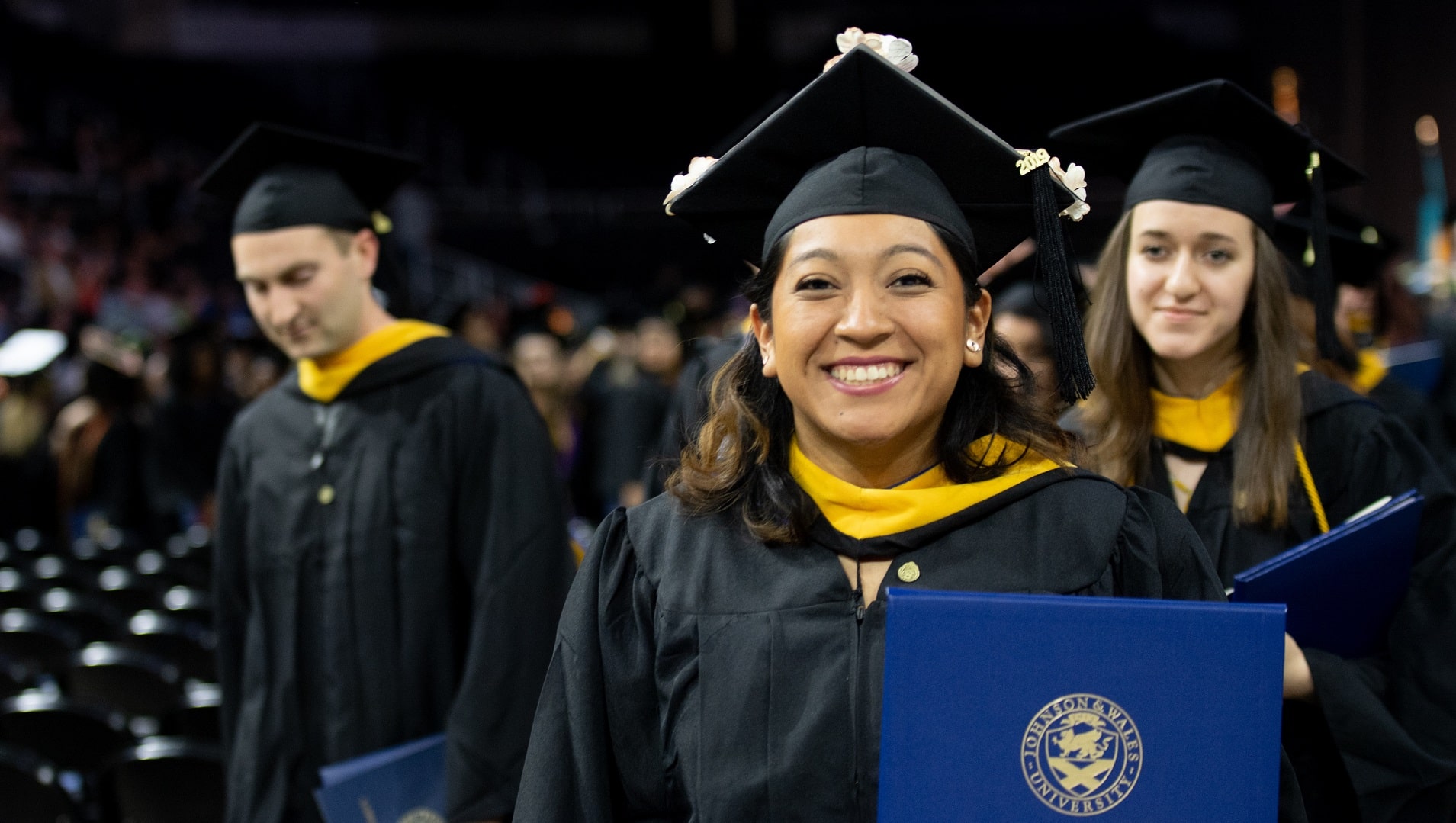 Female student smiles proudly with diploma