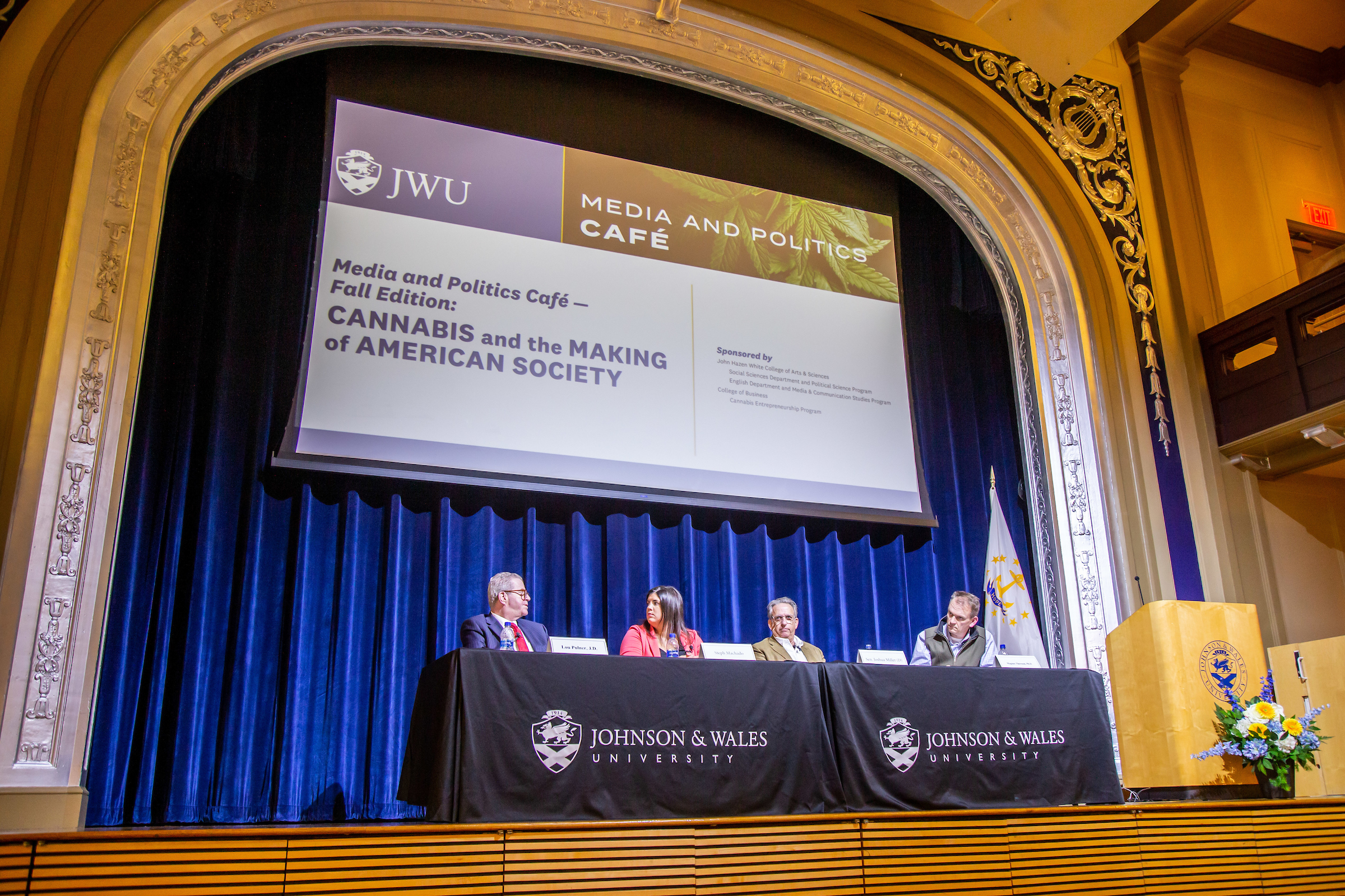 Four speakers on stage: from left to right: Lou Pulner, an attorney from Barrington; Steph Machado, WPRI investigative reporter; RI State Senator Joshua Miller, and JWU Professor Magnus Thorsson, Ph.D.