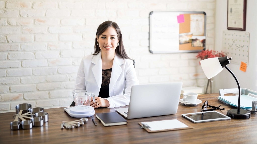 A culinary nutritionist sitting at a desk smiling