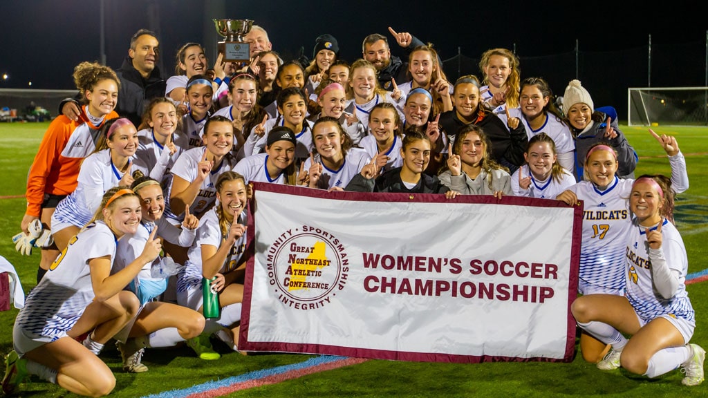 The JWU Women's Soccer team proudly holds up its GNAC 2021 Champions banner