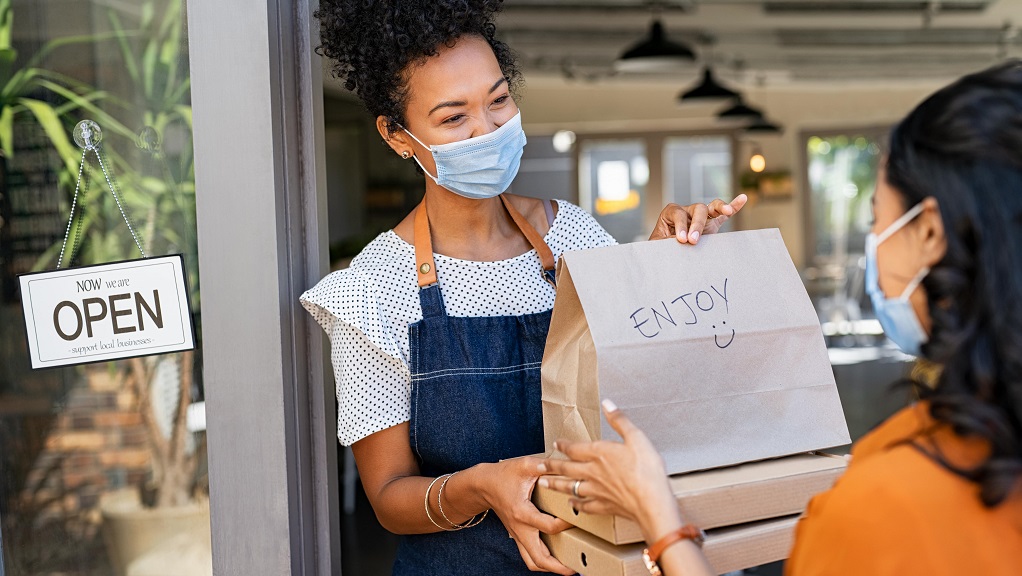 Server with mask gives takeout to customer