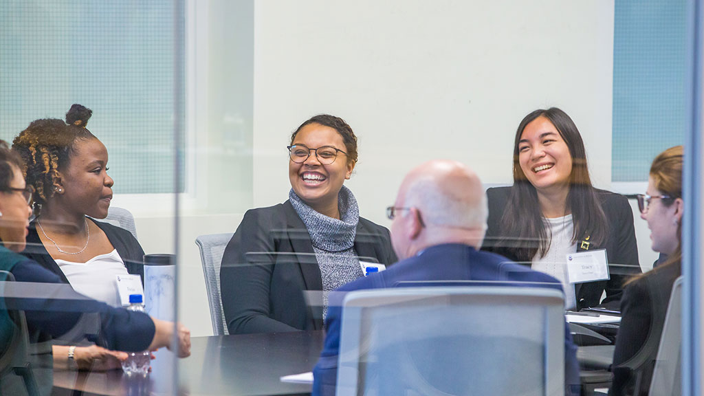 a group of professionally dressed students meet together in a classroom