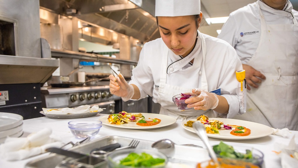 JWU student plating up a colorful dish.