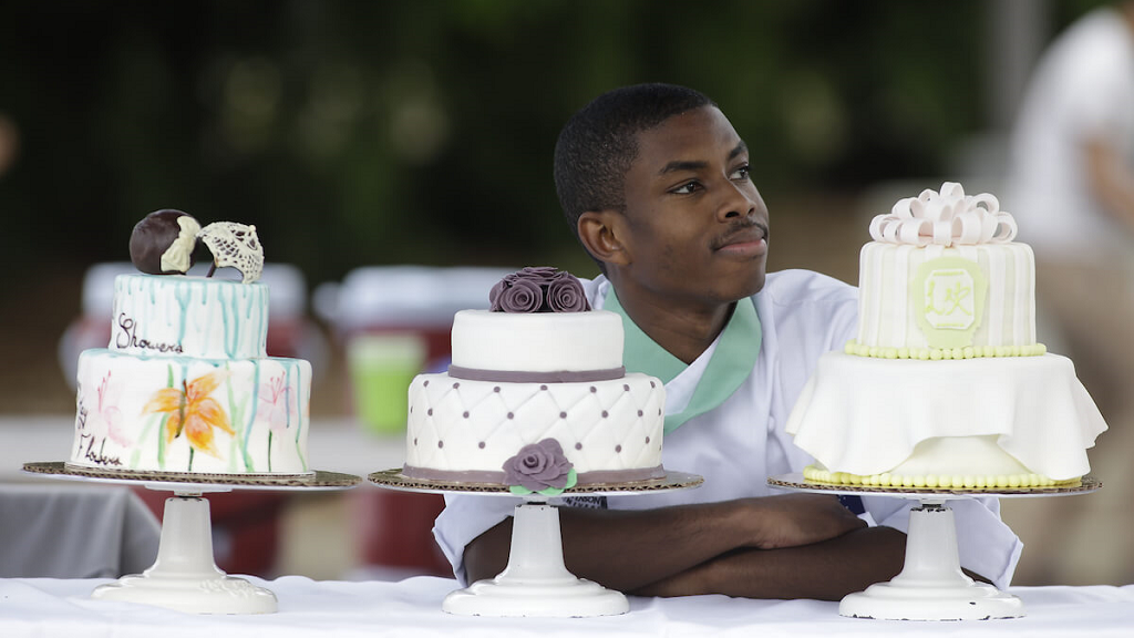 culinary student with assorted cakes