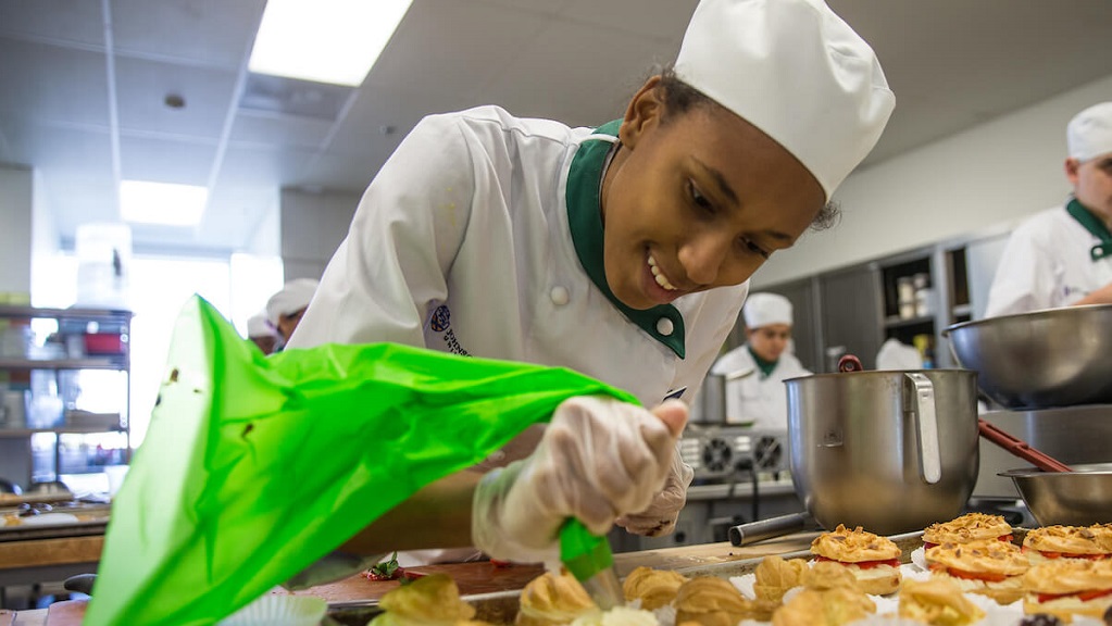 culinary student using piping bake on dessert