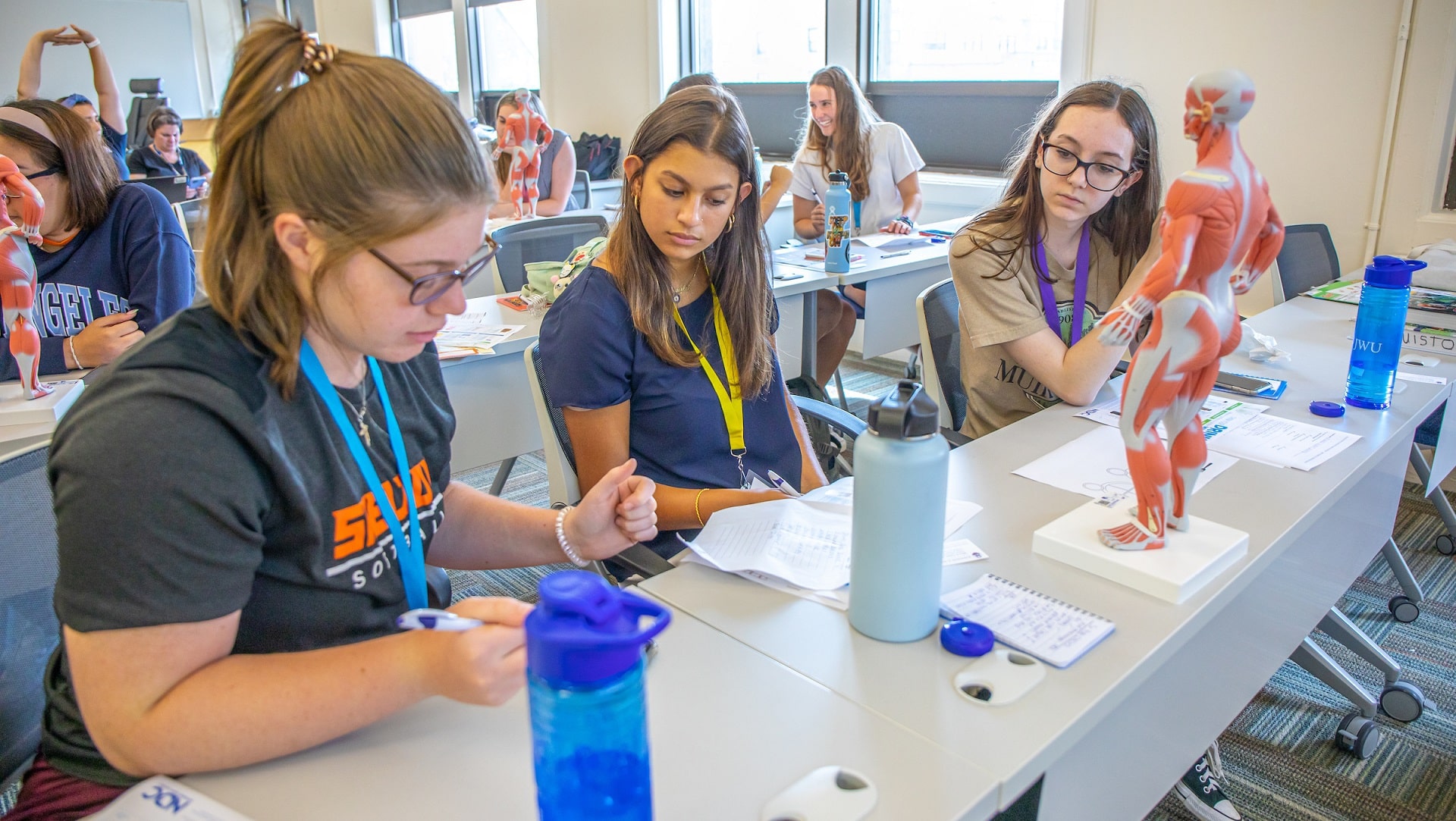 Three female students look at an anatomy model