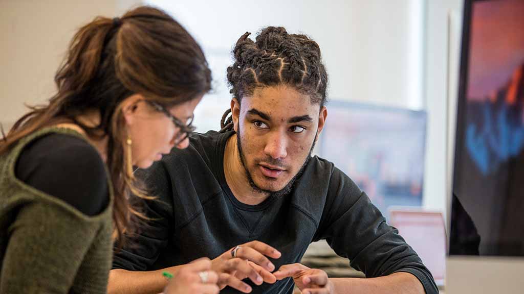 Professor meeting with student and reviewing work