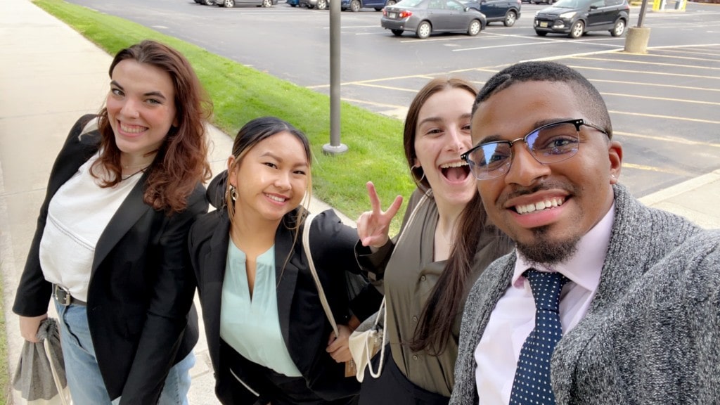 Students waiting for bus in parking lot and taking a selfie