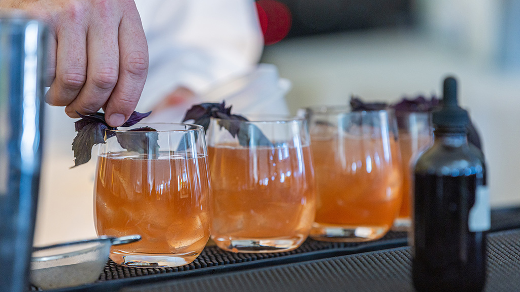 Three glasses of the Purple Bully Smash drink with purple basil leaves on top