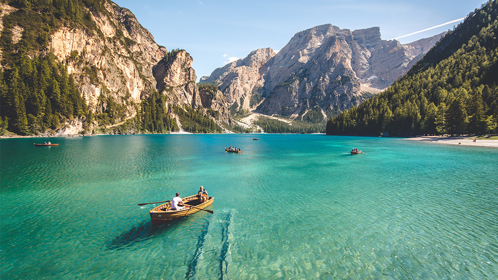 Aqua body of water surrounded by cliffs and vacationers rowing