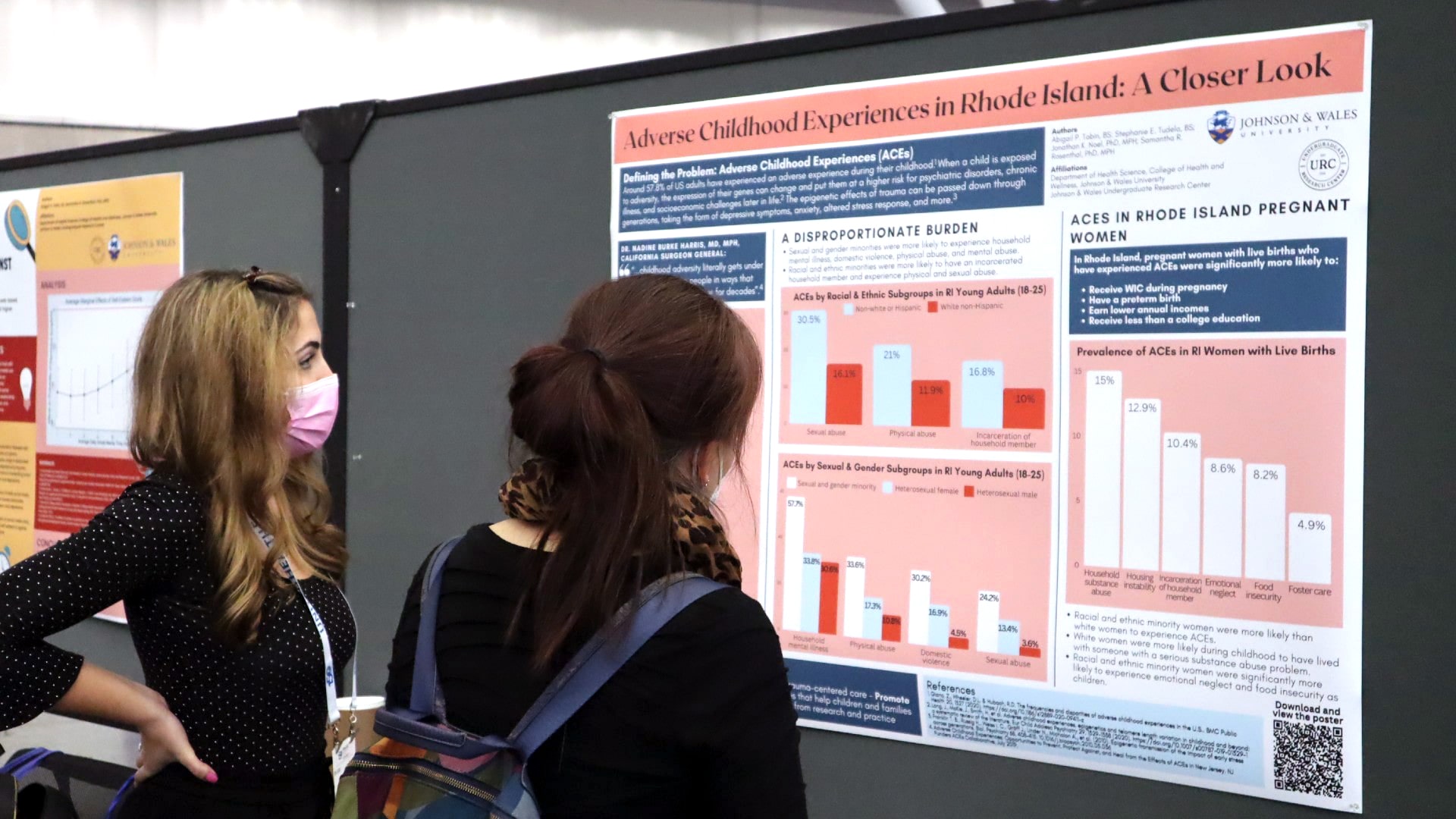 Two attendees of the undergraduate research symposium looking at a poster outlining a research project.