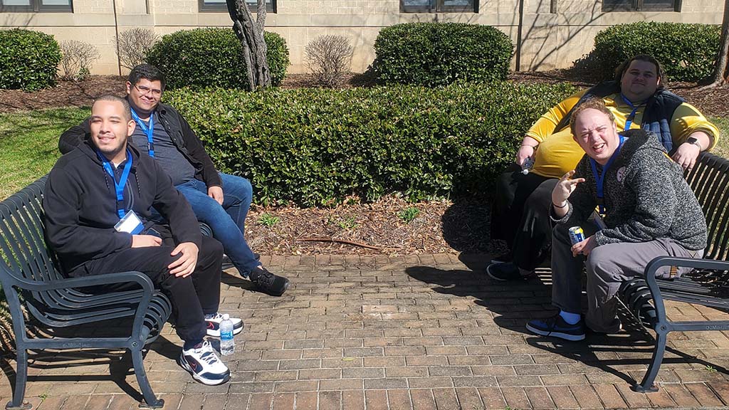 Four students sitting on benches