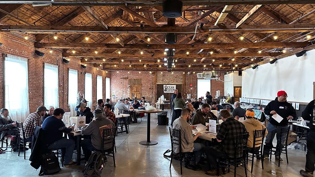 photo showing a large room at the RI Brewers Guild full of tables of people actively judging beer