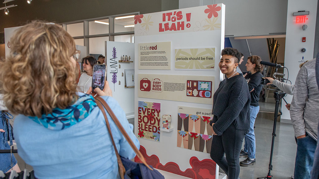 Leah Ward standing next to her design display