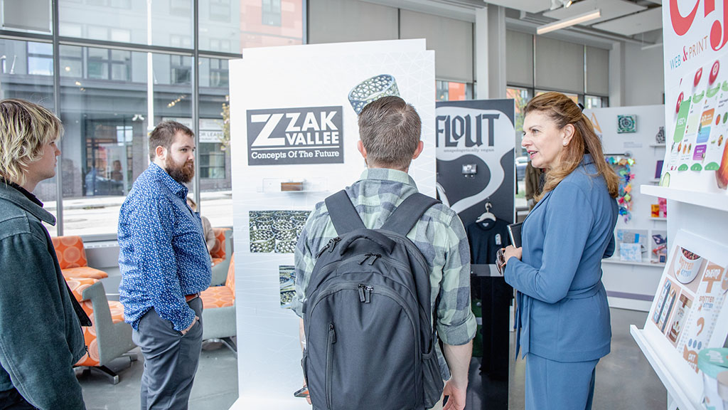 Providence Campus President Marie Bernardo-Sousa talking with students next to a graphic design display