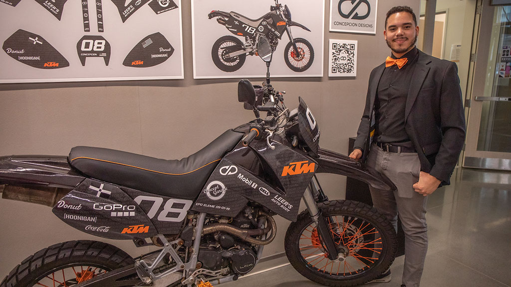 A student standing next to a motorcycle