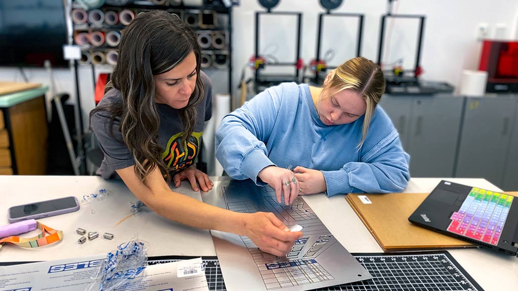 Professor Jimenez-Elliott, left, helps student Shea Lambert on a design for Wayfinding & Environmental Graphics