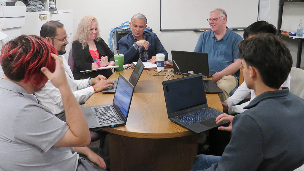 a photo of JWU's ITSS department sitting around a table having a team meeting