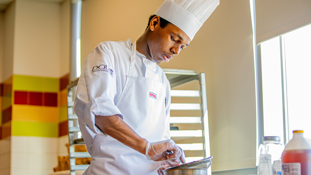 photo of Future Food Competition finalist Brock Green concentrating as he prepares his dessert