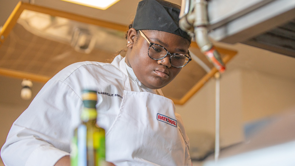 a photo of Gabby Smith concentrating as she prepares food in a kitchen