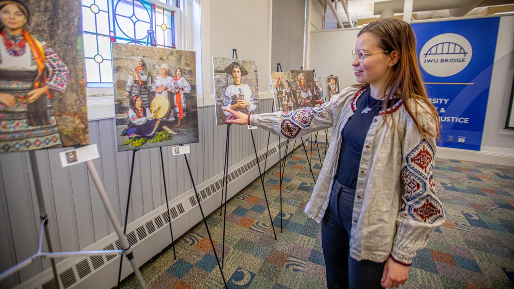 a woman points to artwork on an easel while discussing its contents