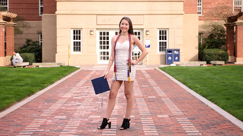 Julia Shiels posing with her graduation cap in Gaebe Commons.