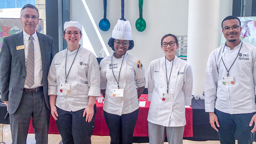 photo of JWU Charlotte Campus President Richard Mathieu posing with students Rachel Littlejohn ’24, Micah Sullivan 24, Anya Glessman ’24 and Marshall Davis ’24 