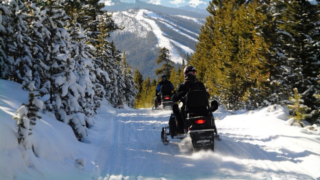 a photo taken of snowmobilers on a mountain trail