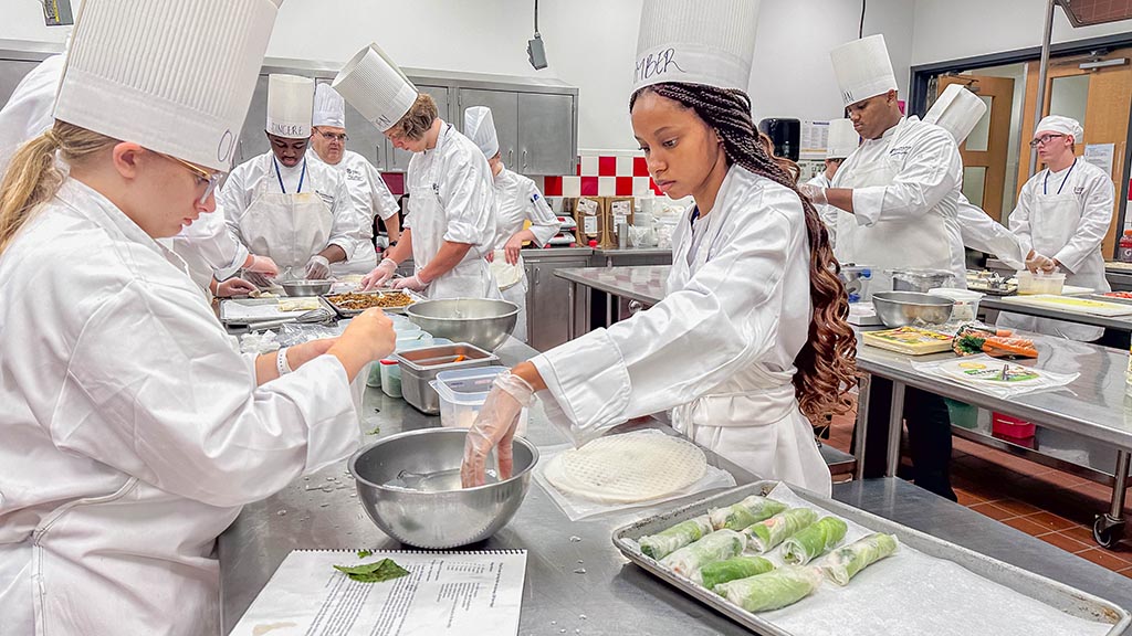 Students prepare fresh spring rolls using rice paper.