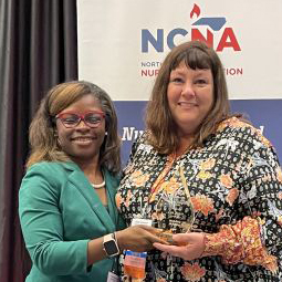 a photo of Lisa Foster, right, being presented with an NCNA award