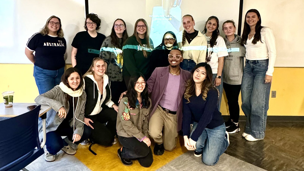 group shot of alum Amir Henley posing with a classroom of JWU students