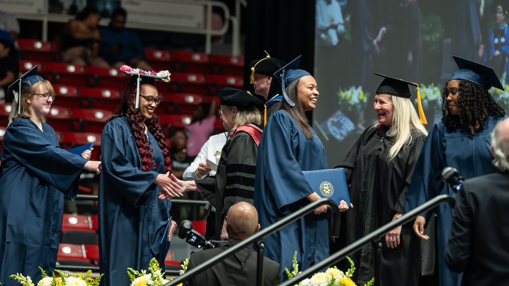New grads advancing across the stage during Commencement.