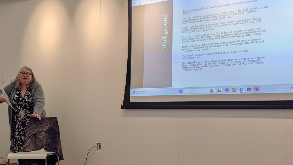 action photo of Professor Kordas lecturing next to a screen