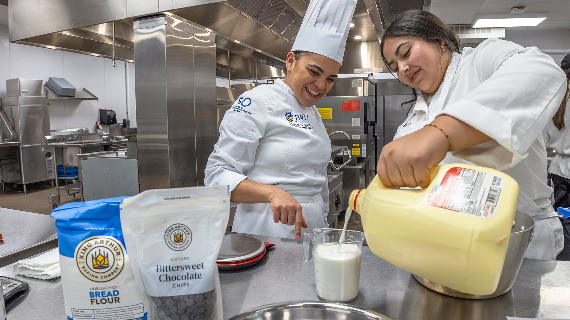 Chef instructor helps a student measure milk.