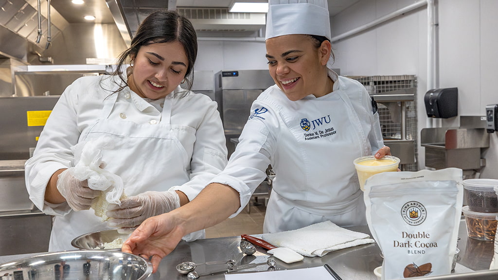 Student removes ingredients from plastic while chef instructor reaches for a bowl next to her