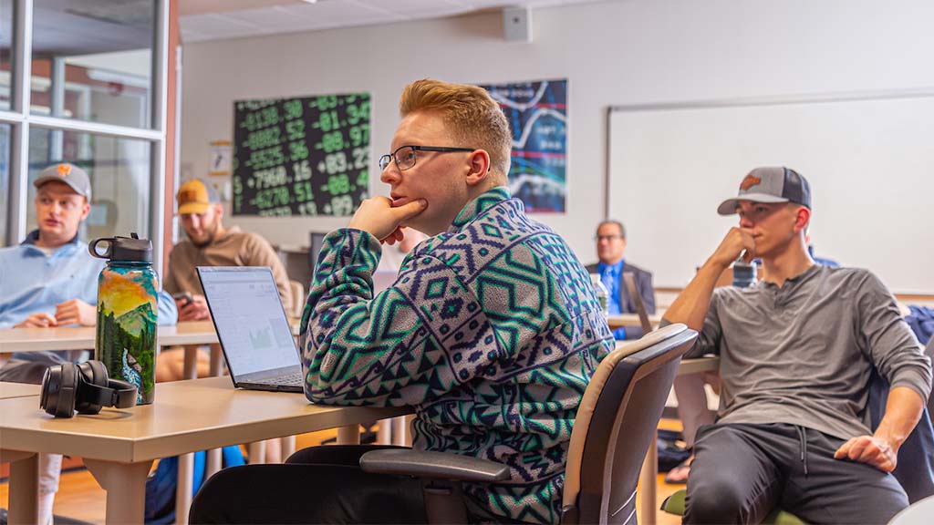 A group of students listen attentively in the Finance & Strategy Center at JWU.