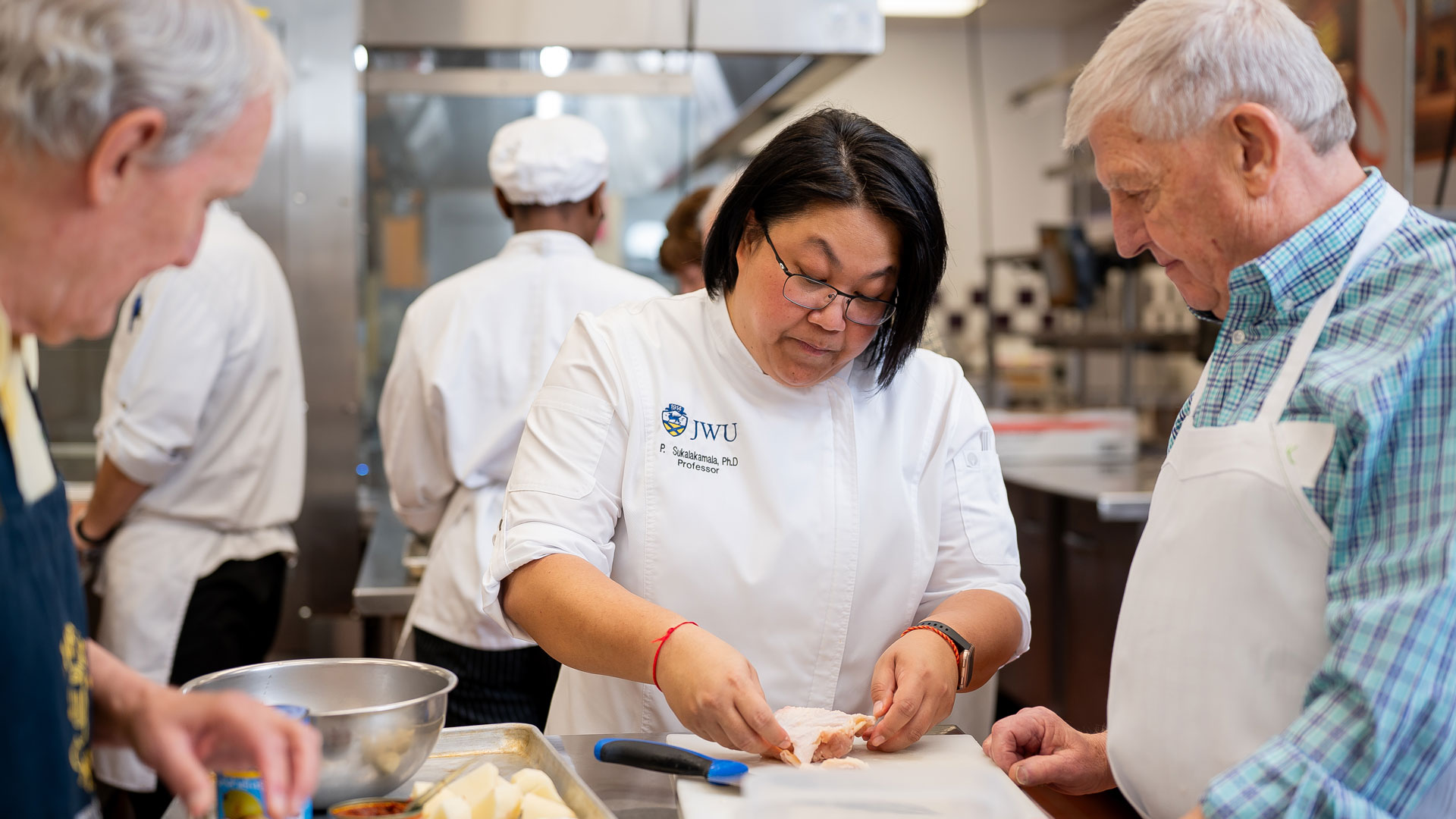 an action shot of Professor Sukalakamala demonstrating a kitchen technique in a recreational JWU cooking class