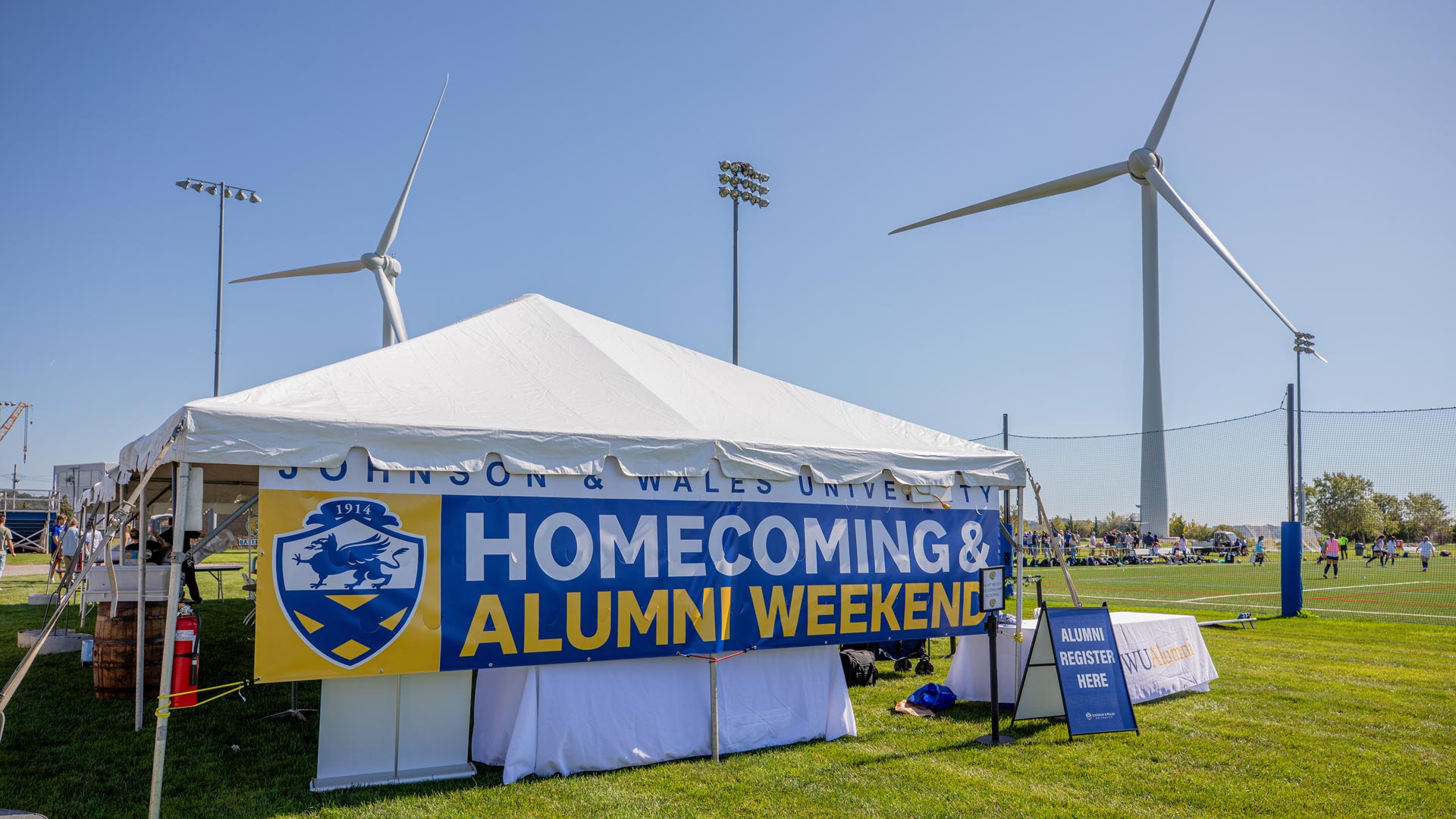 A tent with a banner reading Homecoming & Alumni Weekend