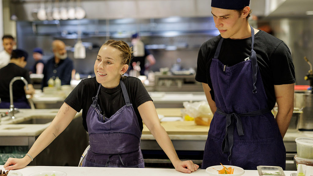 Charlotte Brecher ’18, executive pastry chef at The Modern (left); Daron Sklar '27, pastry line cook at The Modern (right); both wearing black shirts and denim aprons.