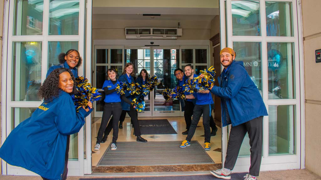 CAT ambassadors holding pom poms in a doorway welcoming students
