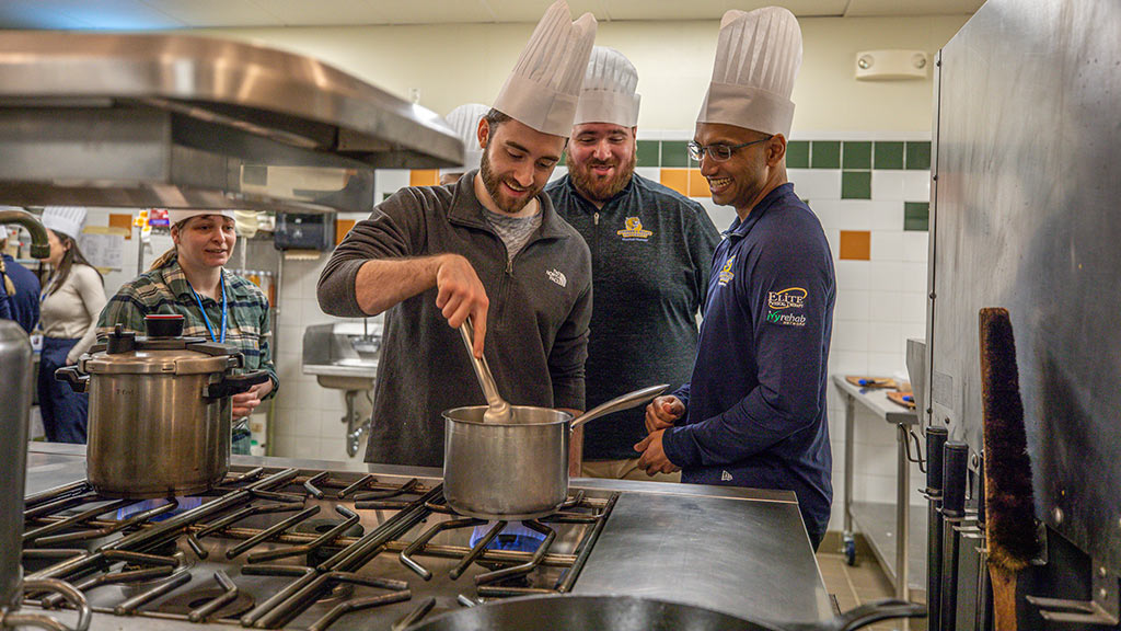 photo of three DPT students at a stove burner in a culinary lab