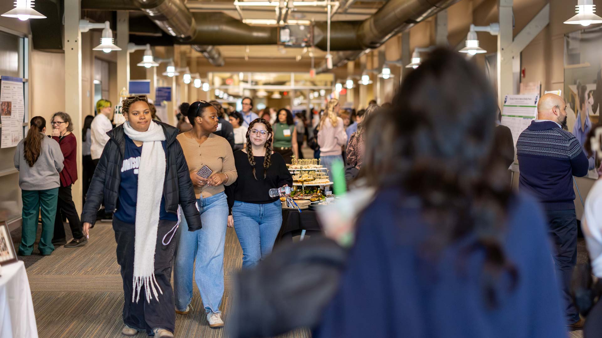 People walking around looking at student's projects at the Symposium