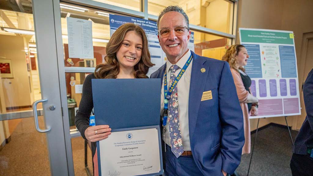 One of the twelve winners at the Symposium, Emily Garganese,  smiling with President Greene with their award