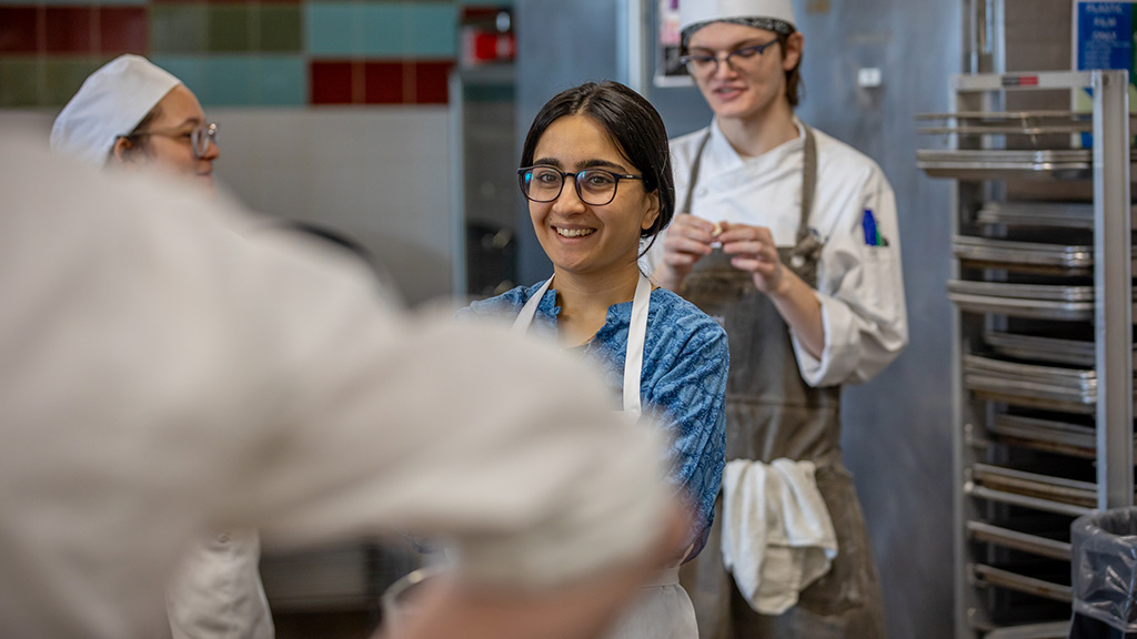 a smiling Naina Qayyum, grad student of Tufts, in a JWU culinary lab
